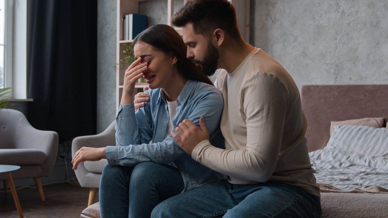 pareja abrazada sentada cama sufriendo dependencia emocional