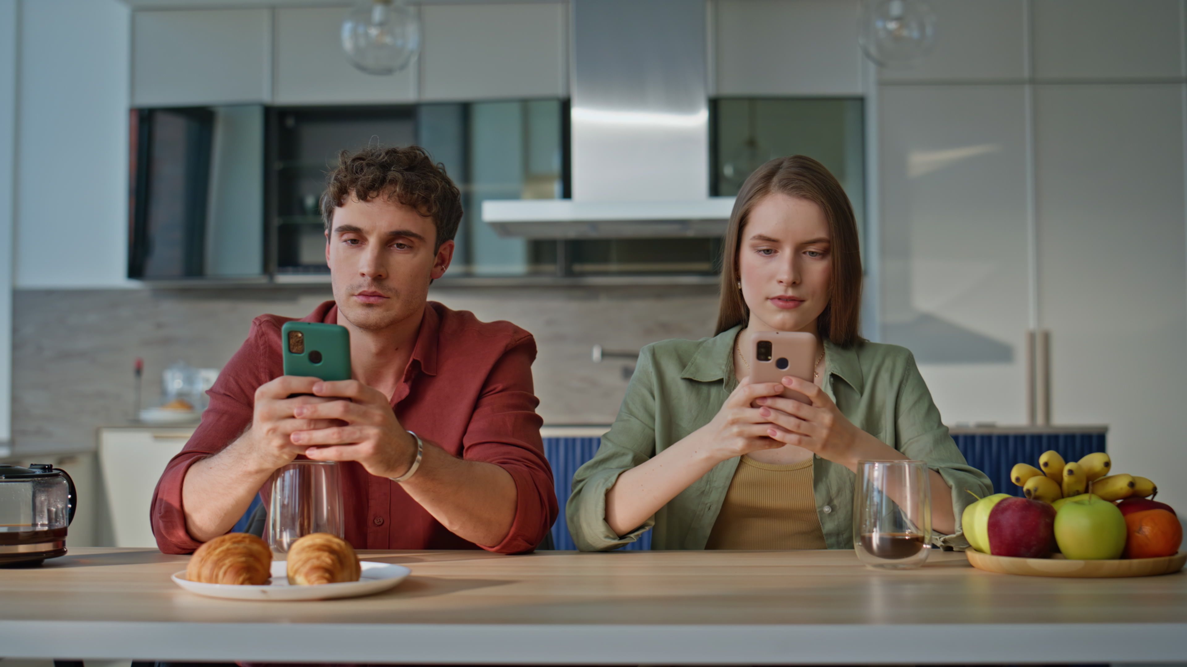 hombre mujer mirando moviles sentados cocina comparacion