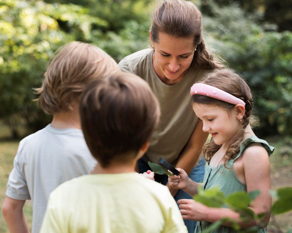 mujer enseñando niños aire libre mirando hojas 