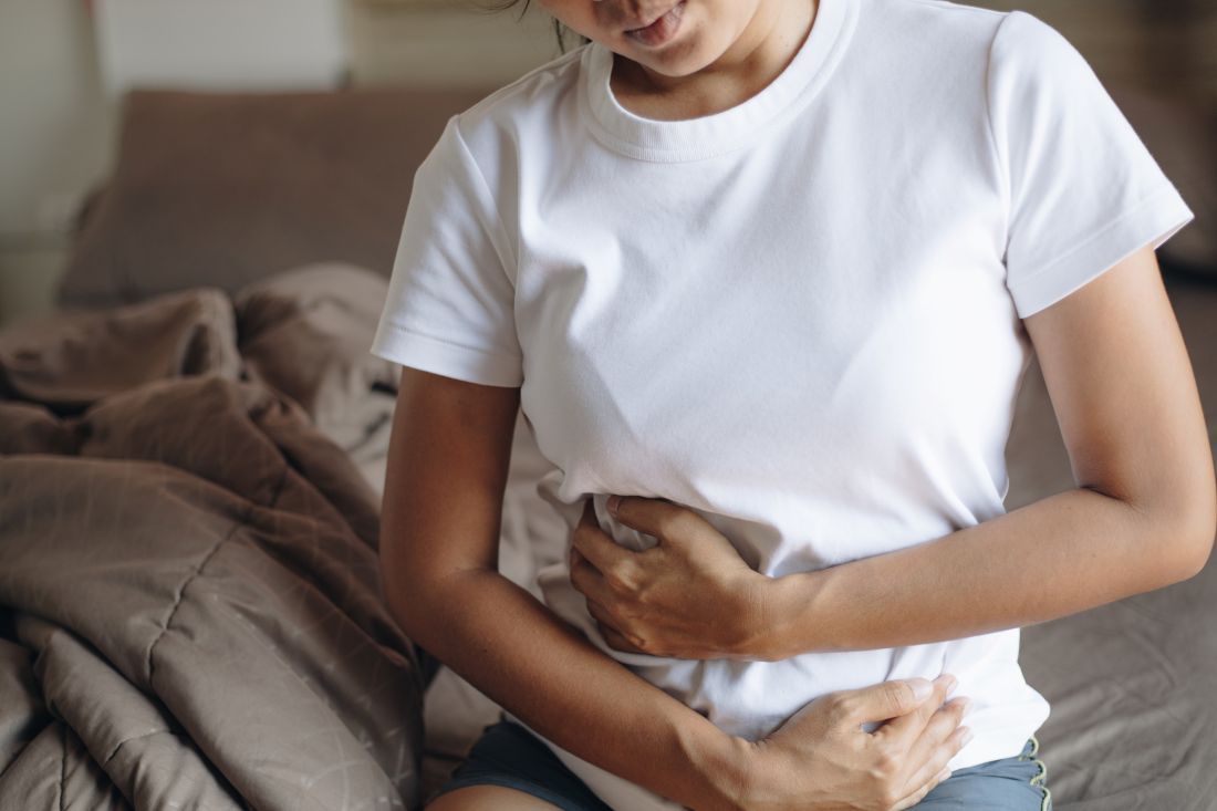 mujer camiseta blanca sentada cama manos tripa dolor 