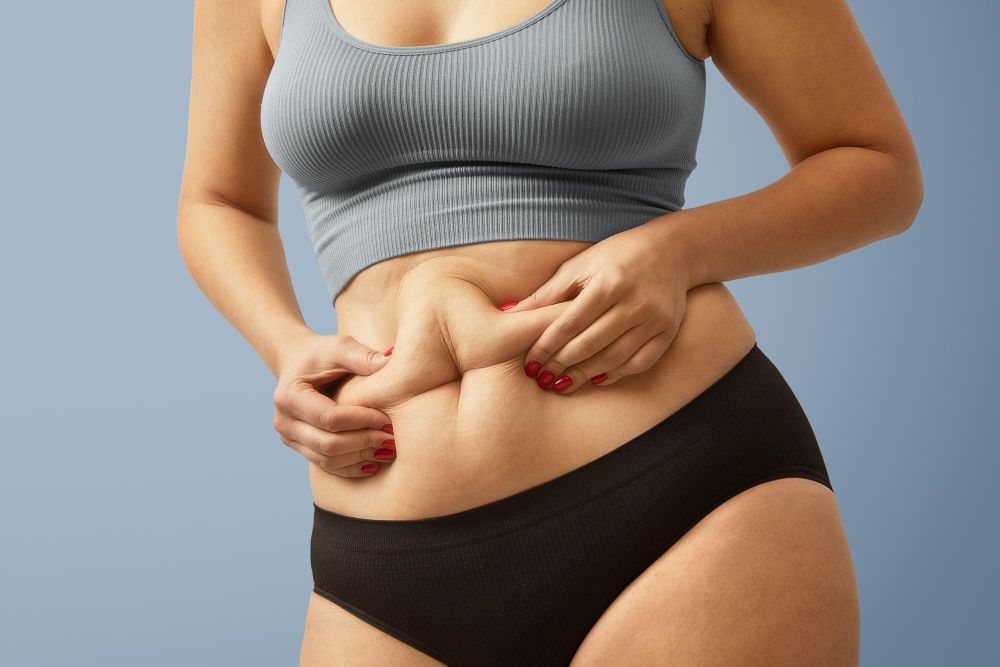 mulher destacando a sua gordura na barriga