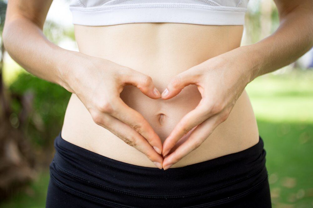 primer plano de manos de mujer formando un corazón sobre el vientre