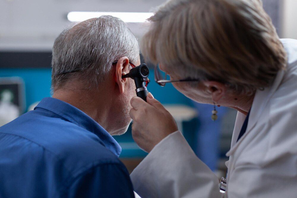 Doctora sosteniendo un otoscopio para realizar una consulta de oído a un hombre mayor en una cita médica. Otóloga usando un instrumento de otología para realizar un examen y dar consejos médicos a un paciente enfermo.