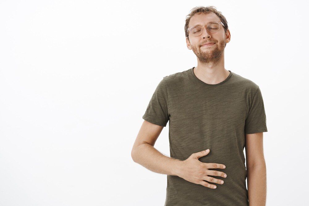 hombre satisfecho y complacido visitando su restaurante favorito, lamiéndose los labios y cerrando los ojos, frotándose la barriga de deleite y satisfacción, sintiéndose lleno tras comer comida sabrosa