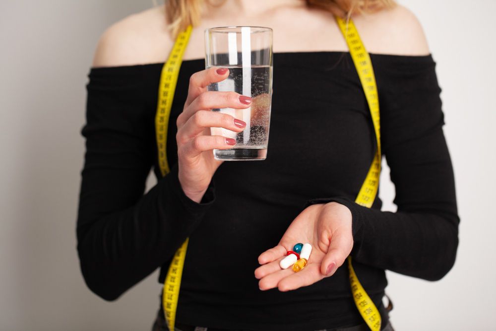 mulher com remedios para emagrecer na mão
