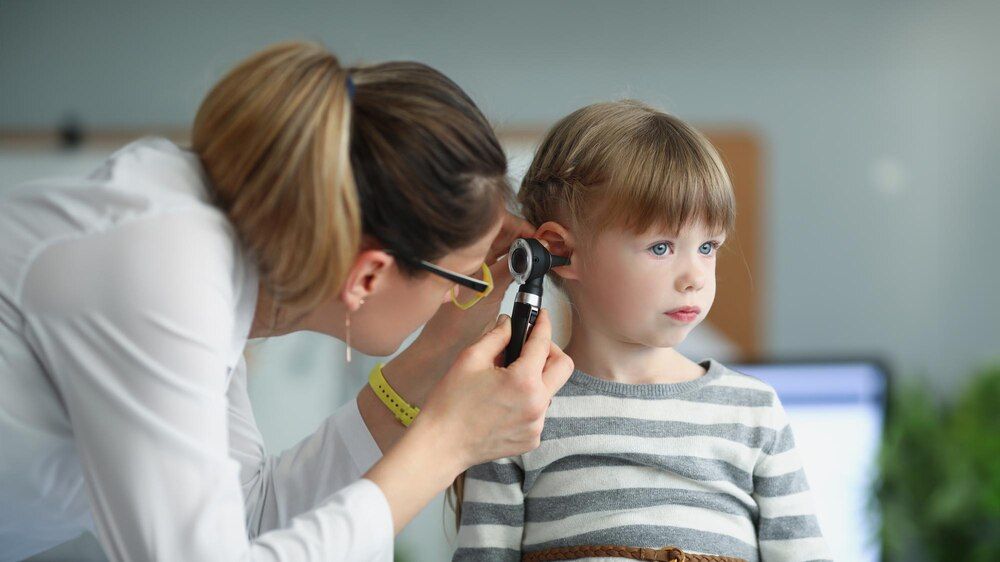 pediatra examinando el oído de una niña con un otoscopio en una clínica