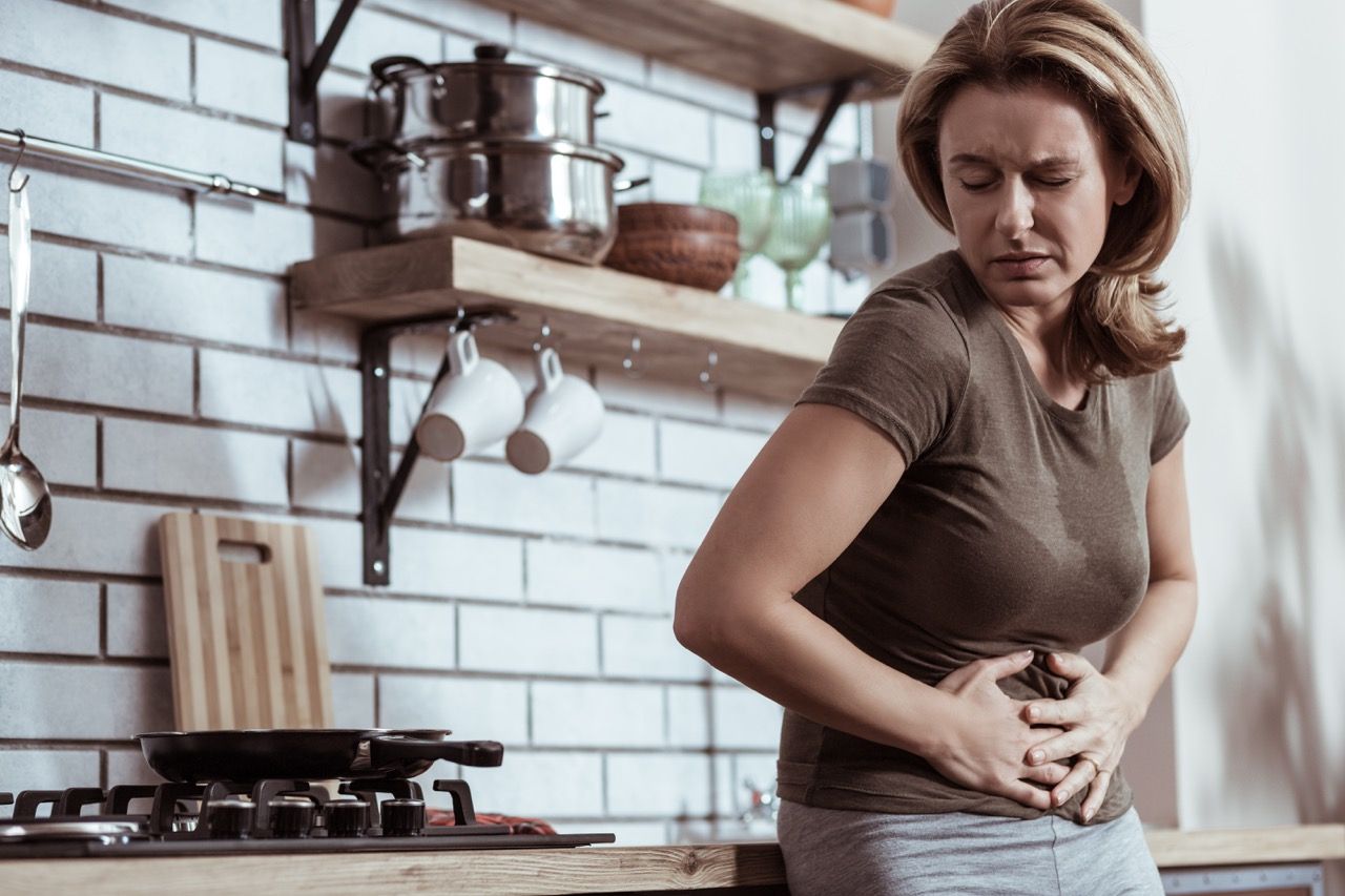 mujer camiseta marron cocina apoyada encimera molestias digestivas