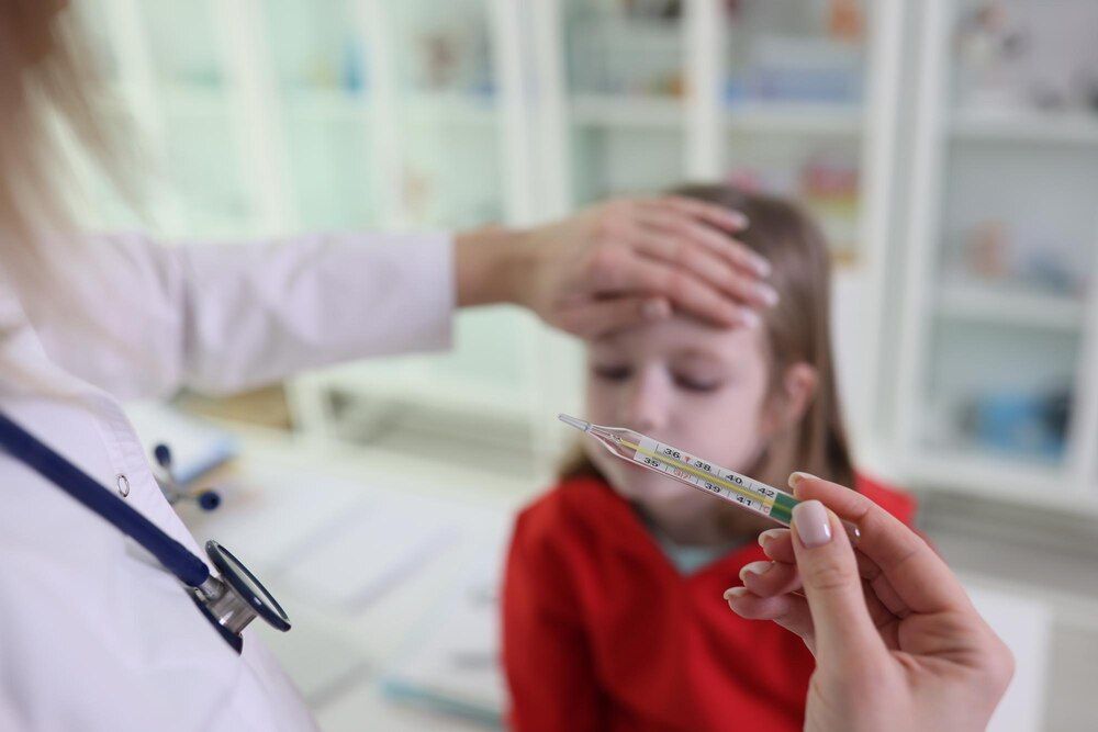 médica pone la mano en la frente de la niña sosteniendo y revisando el termómetro en el consultorio de un hospital doctora