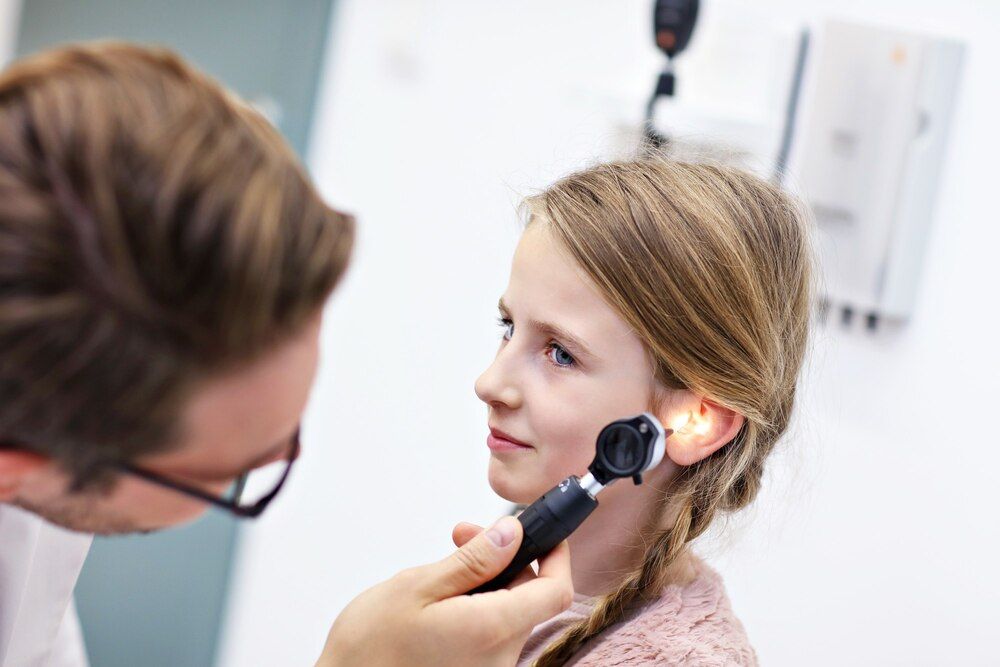 médico examinando el oído de una niña con un otoscopio