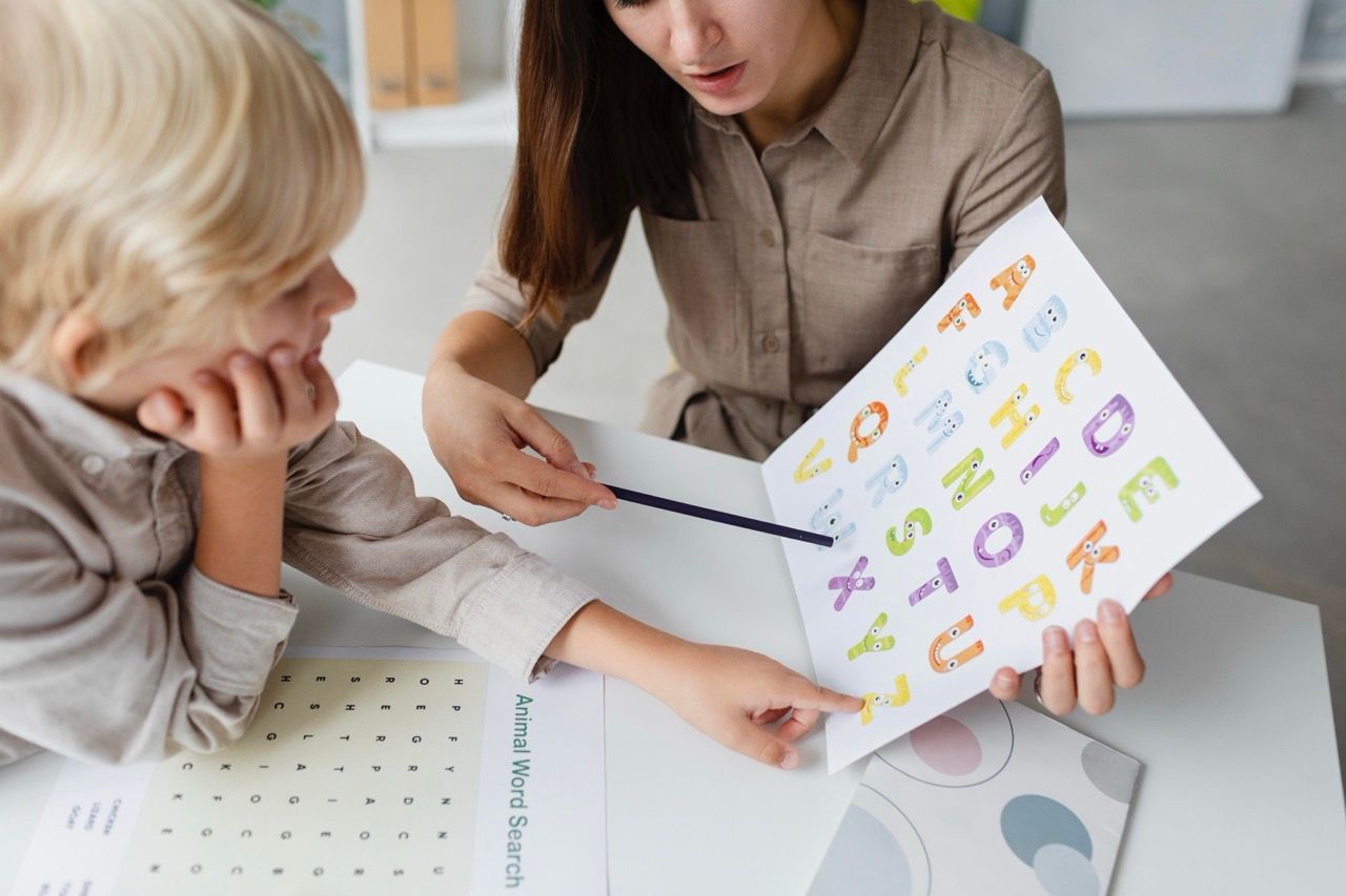 mujer enseñando letras colores cartulina niño dislexia