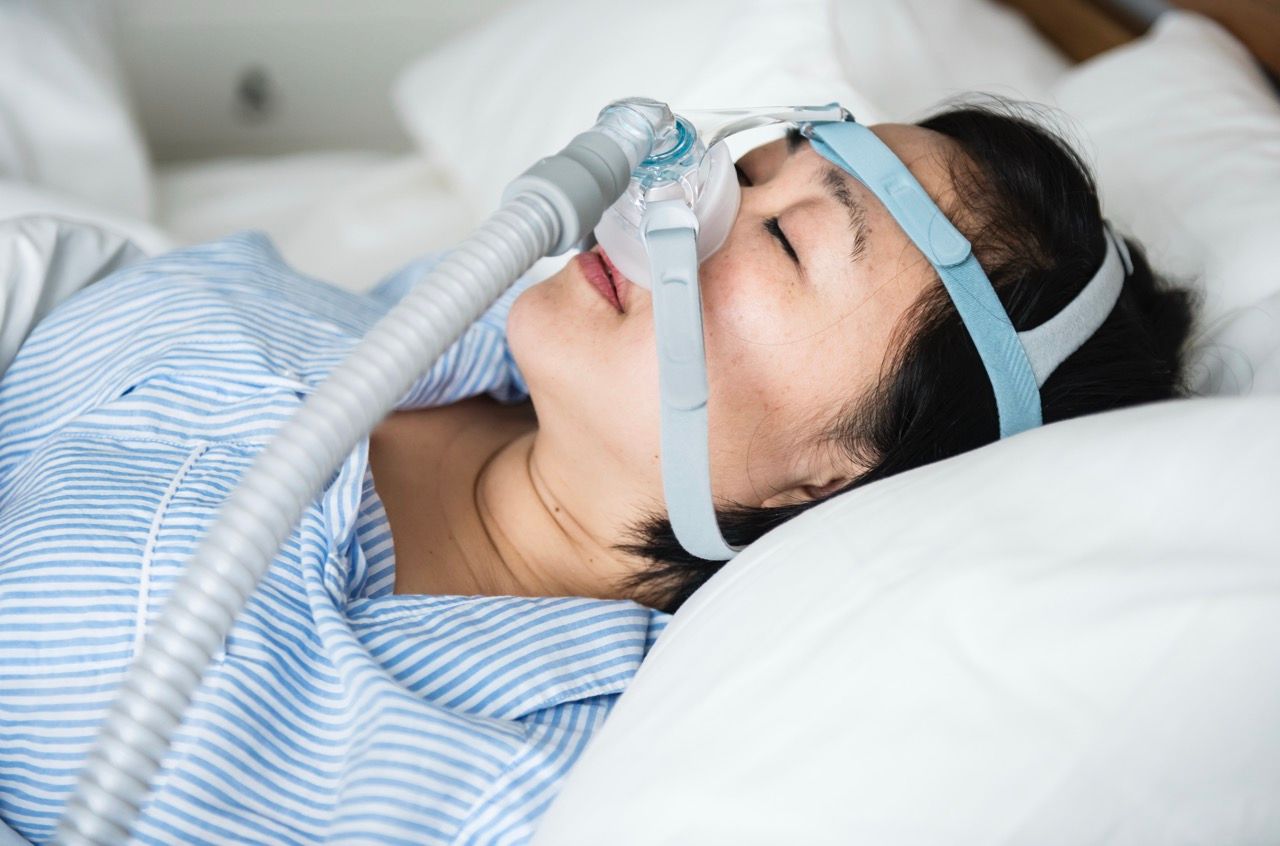 mujer morena asiatica tumbada tubos cara apnea sueño