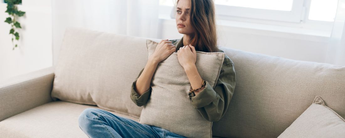 ragazza seduta sul divano prova sensazione di disagio