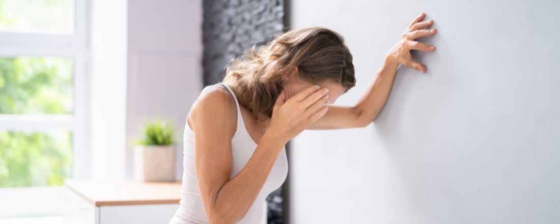 Una donna con vertigini appoggiata ad una parete