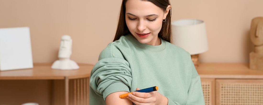 Immagine in primo piano di una ragazza che tiene in mano una penna per misurare i livello di glucosio nel sangue