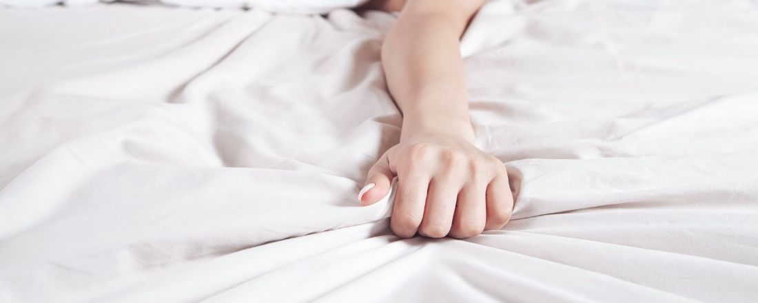 Una mano di donna che stringe un lembo del lenzuolo
