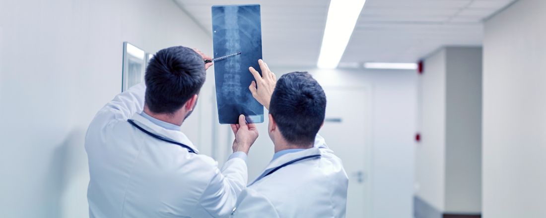 Due medici che osservano la lastra di una colonna vertebrale