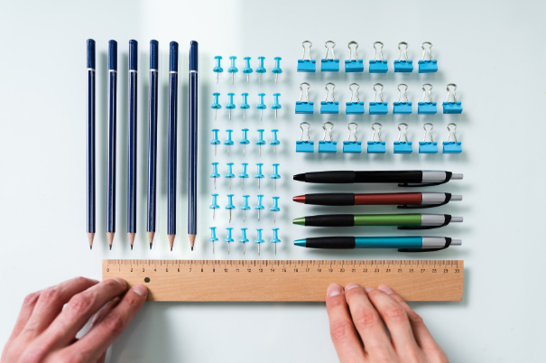 Mani con un righello che misurano le distanze tra oggetti di cancelleria