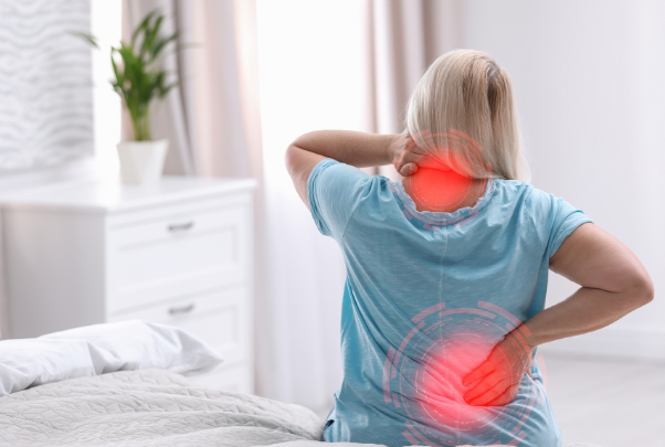 una donna si tocca collo e schiena dopo essersi alzata dal letto