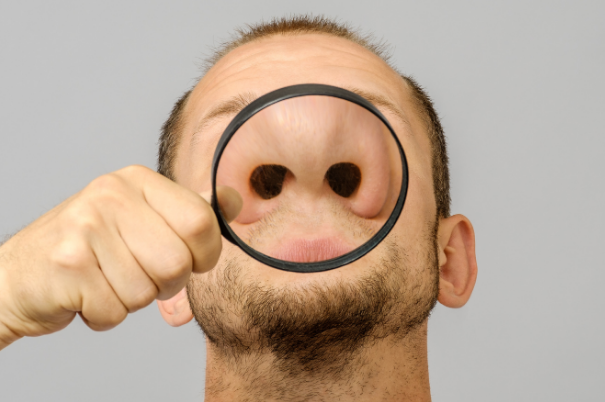 Vivere Senza Olfatto: i Rischi dell'Anosmia Un uomo odora l'ambiente senza recepire gli odori, mentre una lente di ingrandimento sottolinea l'apertura delle sue narici