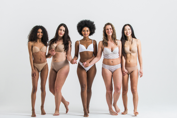 Gruppo di donne di etnia diversa e fisici differenti posano sorridendo e abbracciandosi