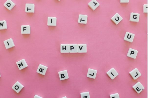 HPV (Papilloma Virus Umano) scritto con Lettere dello Scarabeo su Sfondo Rosa