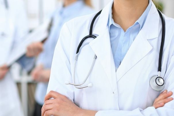 Un Medico di Famiglia con Camice e Stetoscopio Incrocia le Braccia in Primo Piano