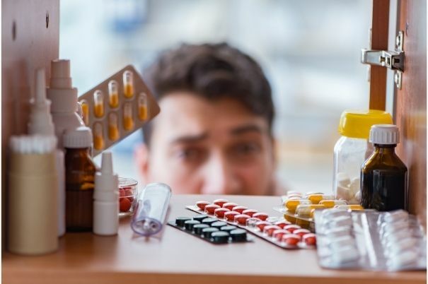 Armadietto Medicinali con Uomo che Sistema Farmaci per Conservarli al Meglio