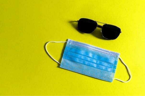 Mascherina Chirurgica e Occhiali da Sole su Sfondo Giallo
