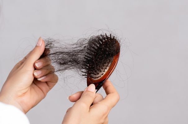 Donna rimuove i Capelli Caduti dalla Spazzola 