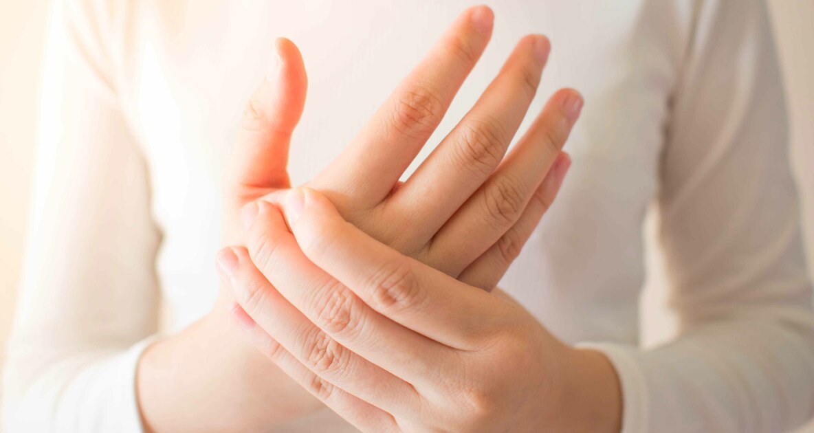 Una persona si tocca la mano