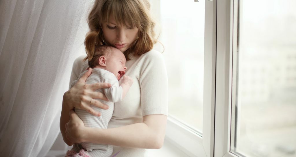 neonato che piange in braccio a una donna