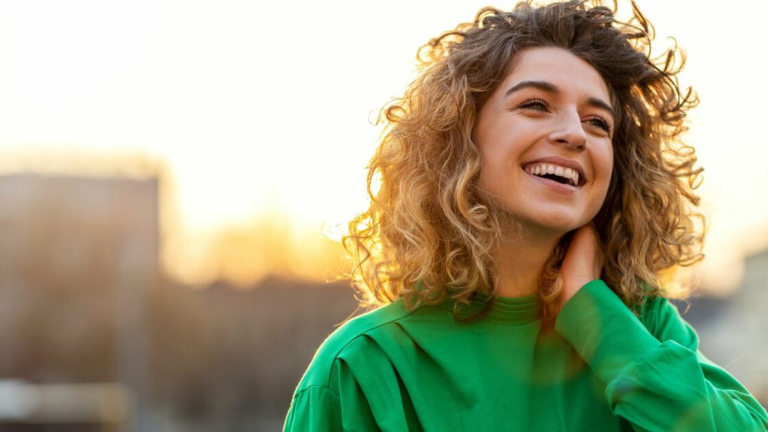 ragazza con capelli ricci sorride al tramonto