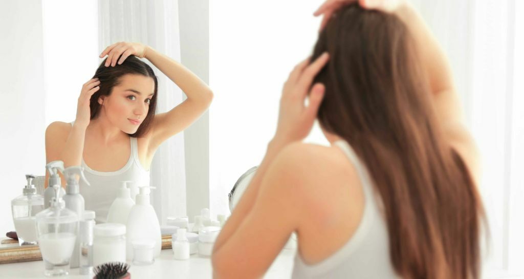 ragazza si tocca i capelli davanti allo specchio
