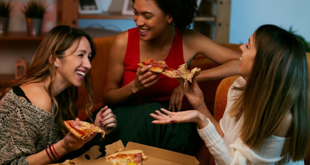 Amiche mangiano la pizza