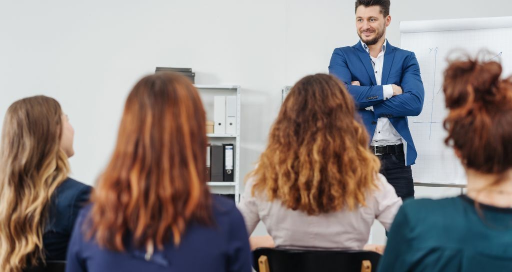 uomo parla in pubblico con le braccia conserte