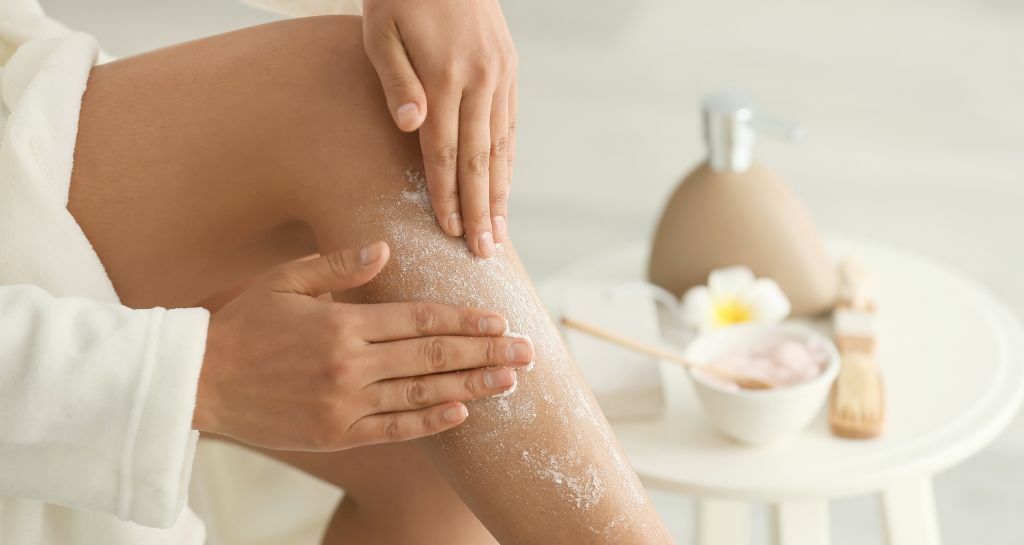 una persona applica lo scrub alle gambe