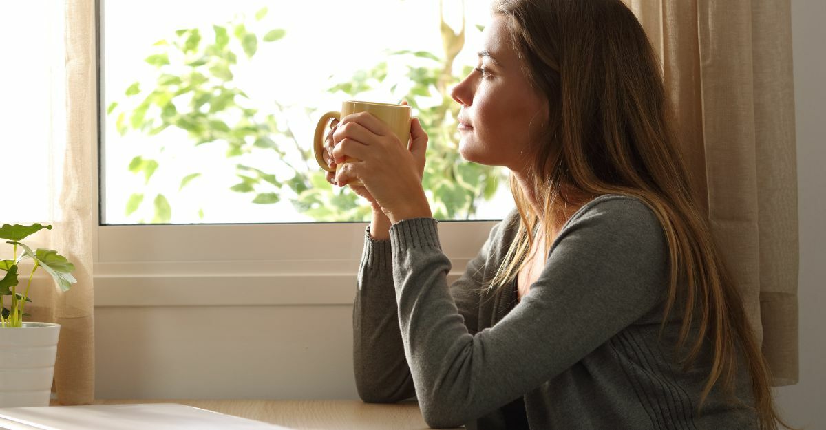 ragazza con una tazza in mano vicino alla finestra