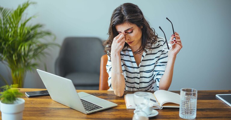 Donna a lavoro davanti al computer con mal di testa