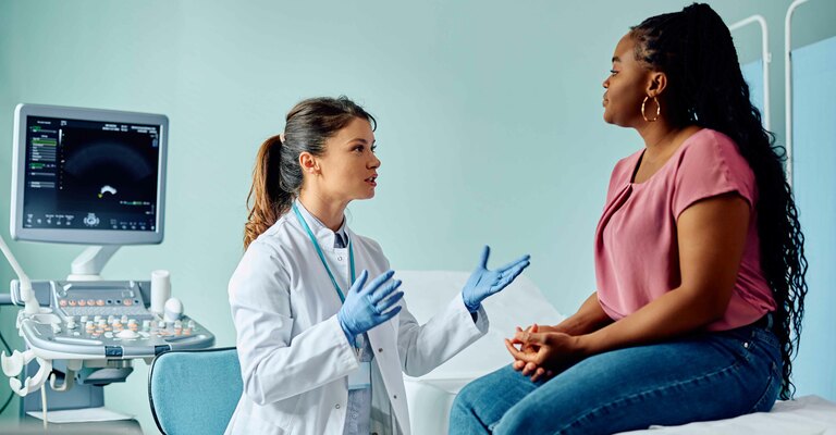 Donna parla con ginecologo su un lettino del suo studio