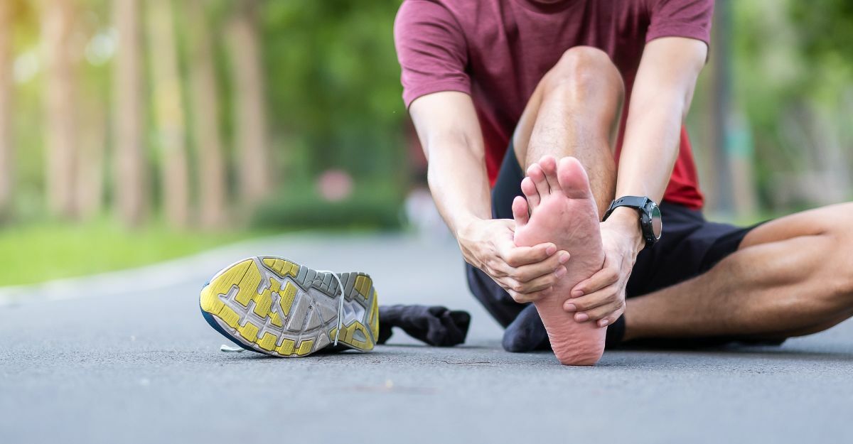 ragazzo seduto per terra si tocca i piedi doloranti