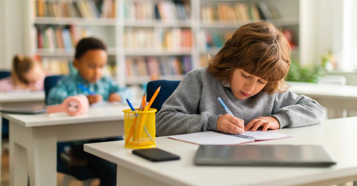 Bambino a scuola scrive su un quadernetto