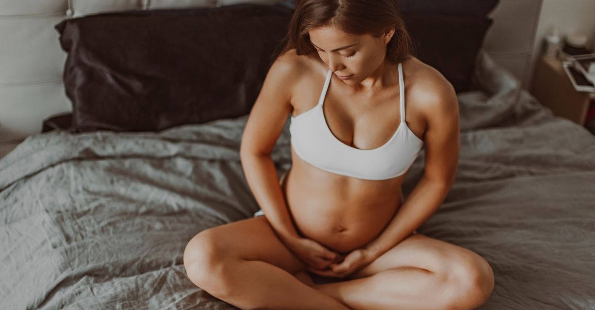 donna incinta seduta sul letto mangia