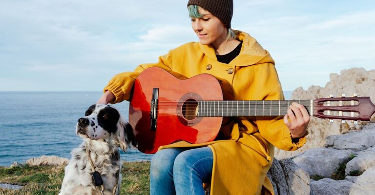 ragazza che suona la chitarra vicino ad un cane