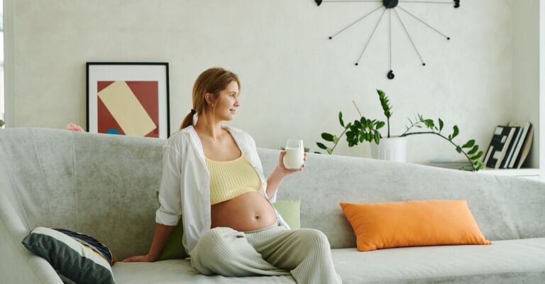 donna incinta beve latte sul divano