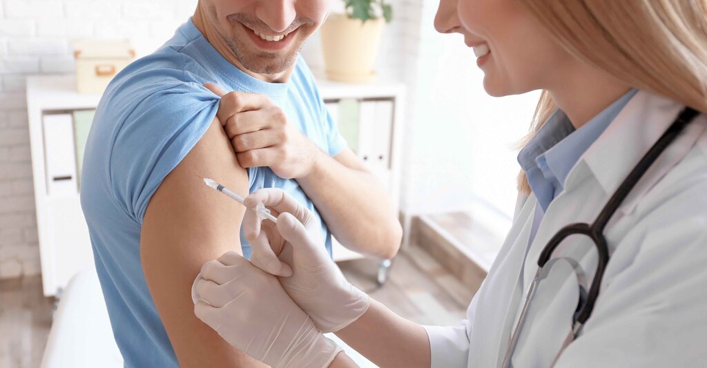 Medico con siringa si avvicina al braccio del paziente per vaccinarlo