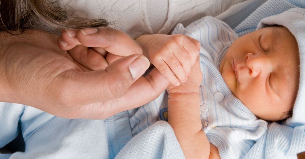 neonato tiene il dito della mamma