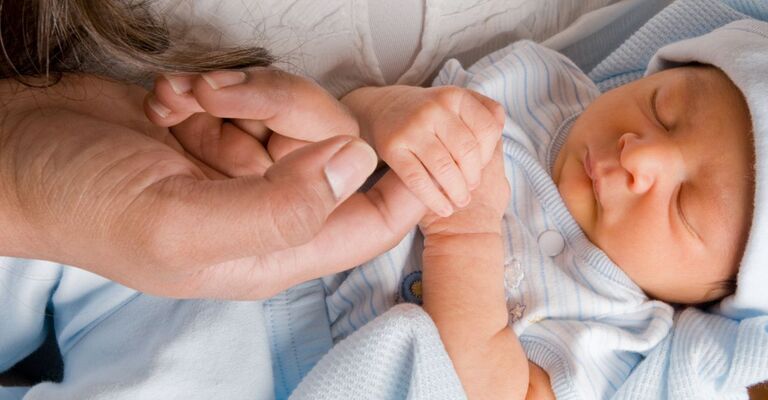 neonato tiene il dito della mamma
