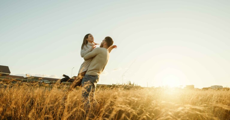 Coppia si abbraccia in un campo giallo al tramonto
