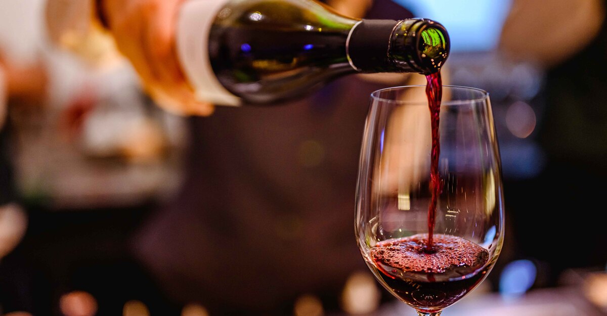 Un cameriere versa del vino rosso in un bicchiere