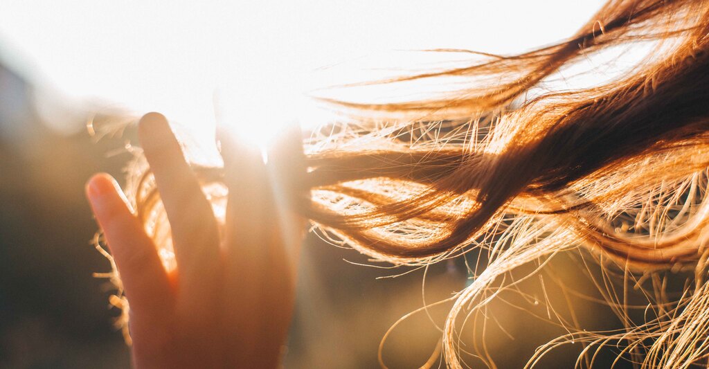Donna si tocca i capelli al sole in controluce
